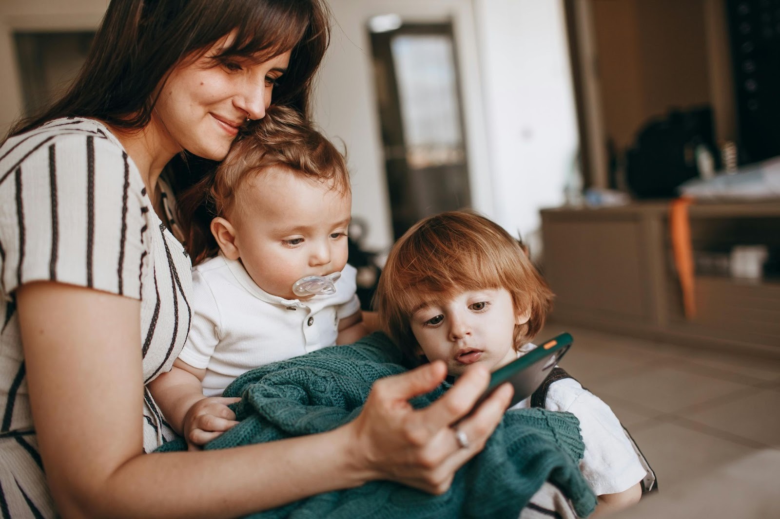 Mother sitting at home with two young children, illustrating the private, everyday moments that require trust, discretion, and sound judgment when hiring a nanny in Washington, D.C