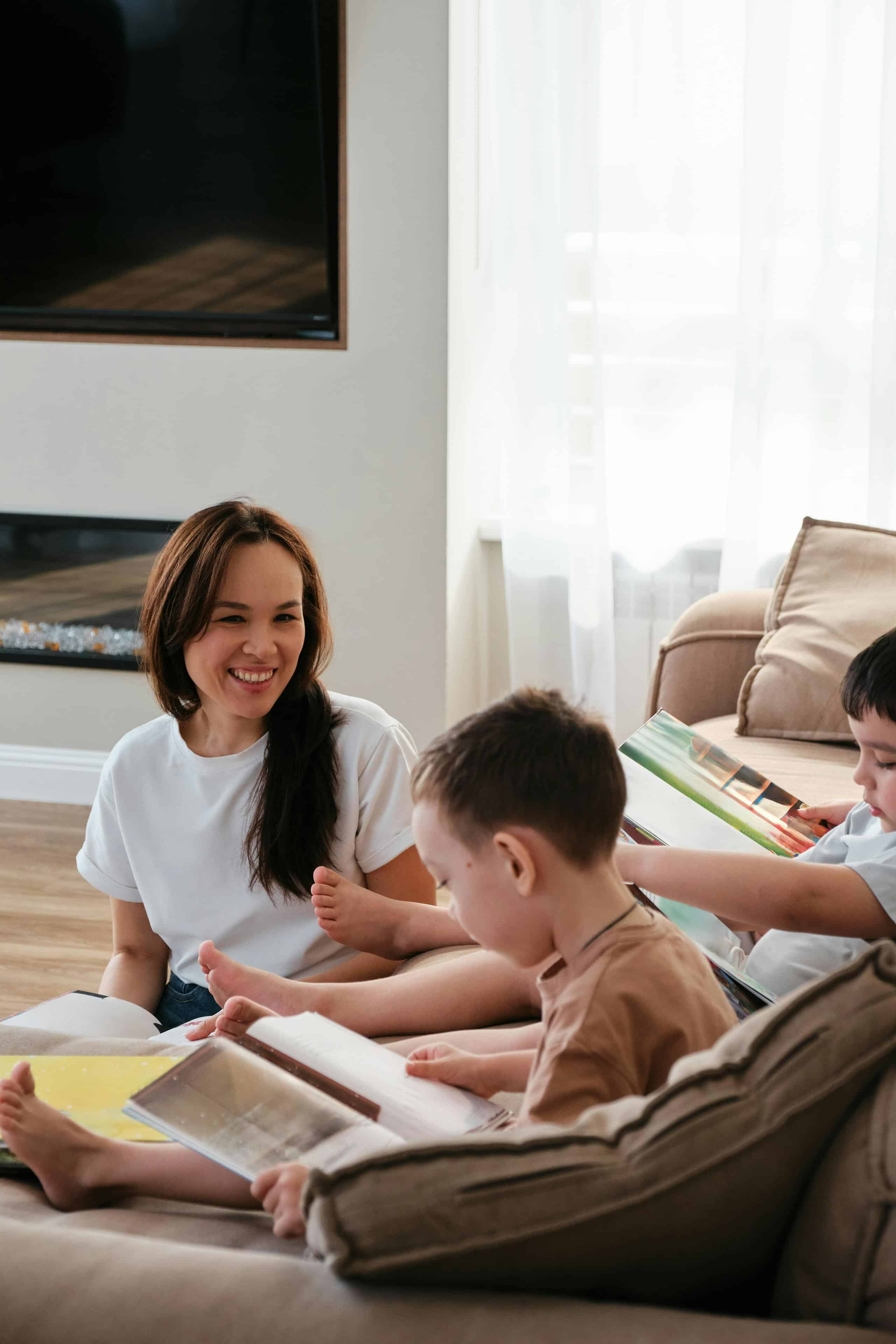A nanny reading with two children on the living room floor of a Cleveland family home