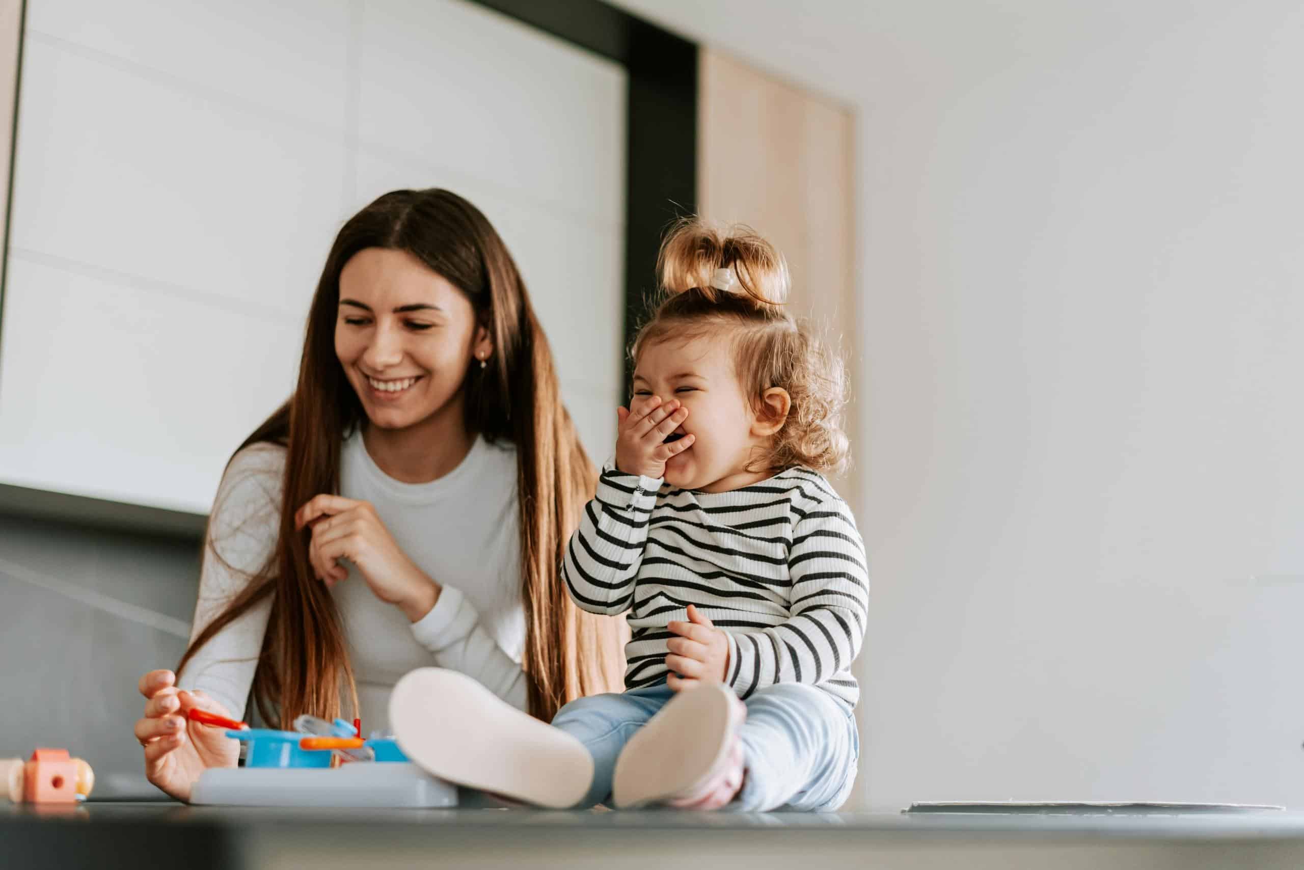 Nanny playing with a giggling toddler and toys on a table in Cincinnati