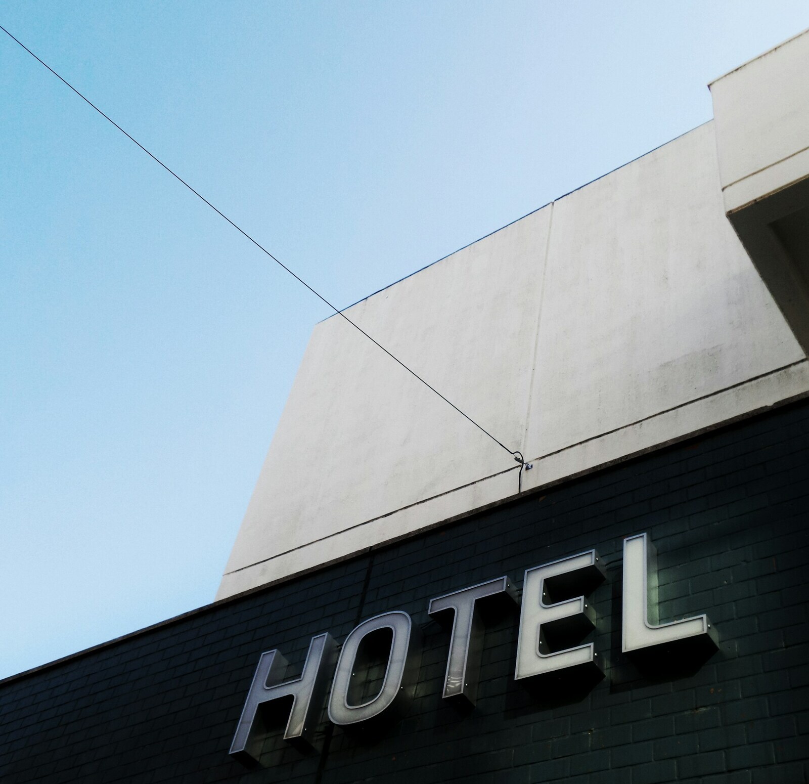 Foto von <a href="https://unsplash.com/de/@possessedphotography?utm_source=unsplash&utm_medium=referral&utm_content=creditCopyText">Possessed Photography</a> auf <a href="https://unsplash.com/de/fotos/schwarz-weisses-hotelgebaude-aus-beton-unter-ruhigem-blauem-himmel-KTyDpKRwhOs?utm_source=unsplash&utm_medium=referral&utm_content=creditCopyText">Unsplash</a>
