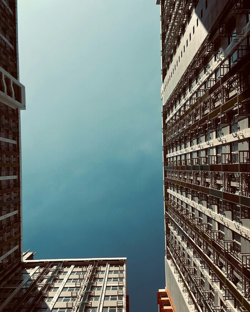 Foto von <a href="https://unsplash.com/de/@kahoooo?utm_source=unsplash&utm_medium=referral&utm_content=creditCopyText">Ka Ho Ng</a> auf <a href="https://unsplash.com/de/fotos/er-blickte-zu-hohen-gebauden-gegen-einen-klaren-blauen-himmel-hinauf-Umn22zhQlXU?utm_source=unsplash&utm_medium=referral&utm_content=creditCopyText">Unsplash</a>
      