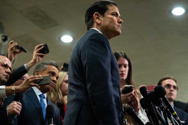 Mr. Rubio listening to a question from a reporter amid a crowd of reporters holding out their phones.