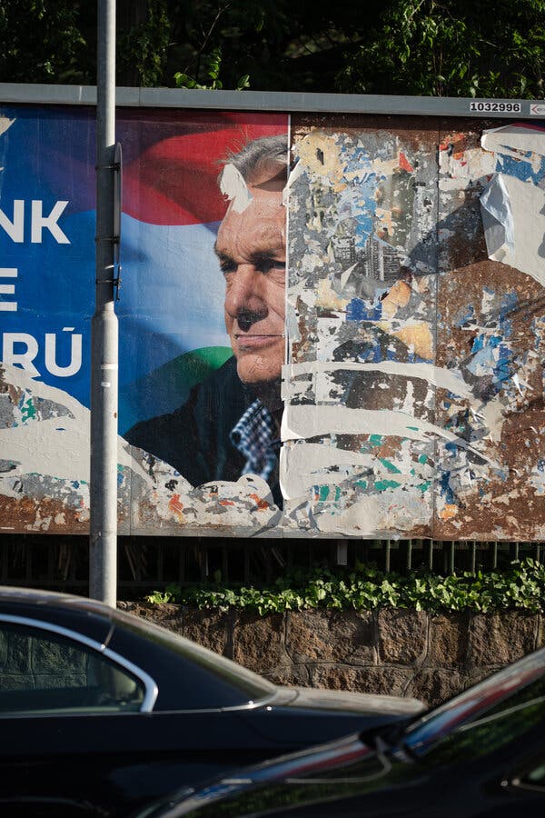 A billboard, half defaced, half showing the face of a man wearing a determined expression.