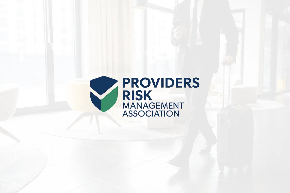 Logo of Providers Risk Management Association with a shield icon in blue and green, over a blurred background of a person walking with a suitcase in an office lobby.