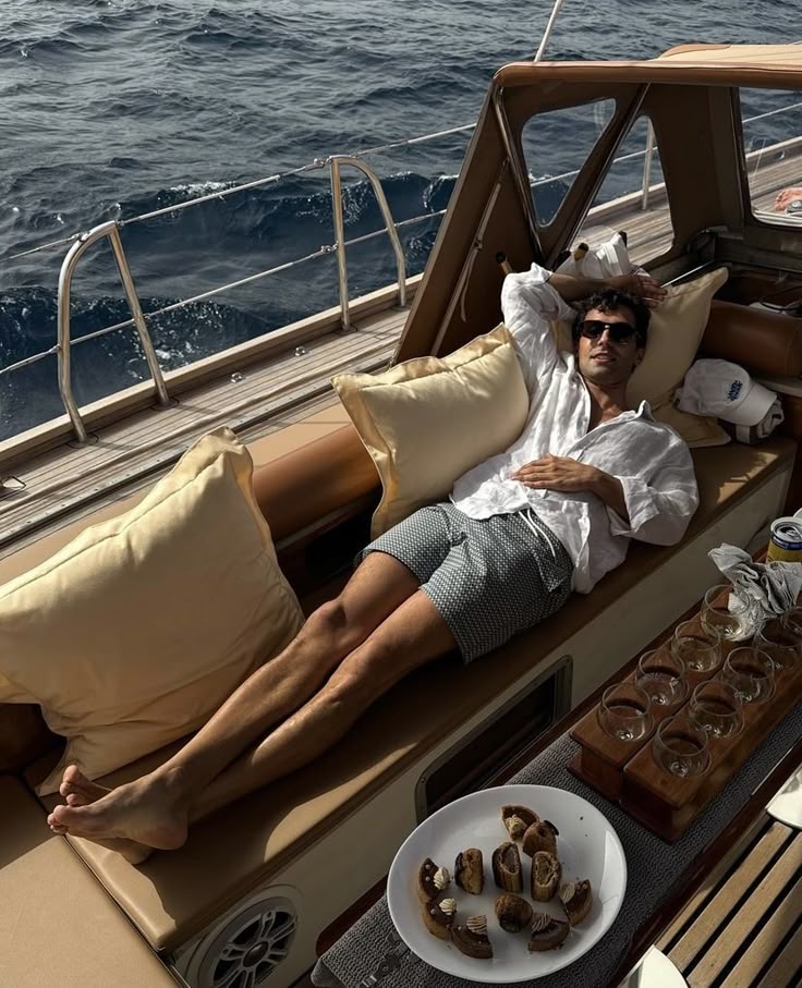 Three women wearing white winter outfits and pink boots sitting in deck chairs in snow next to a teepee and fire pit, smiling and waving.