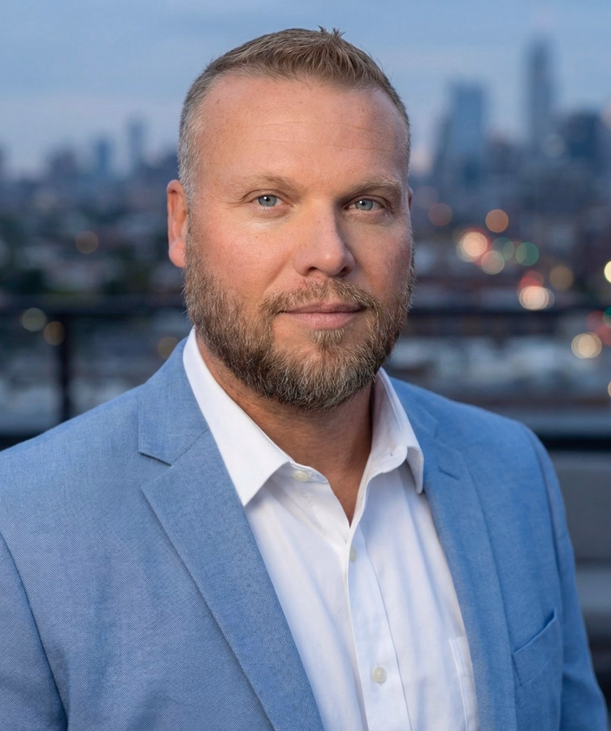 NextLink Capital founder Michael Hohenberg in front of blurred cityscape background.