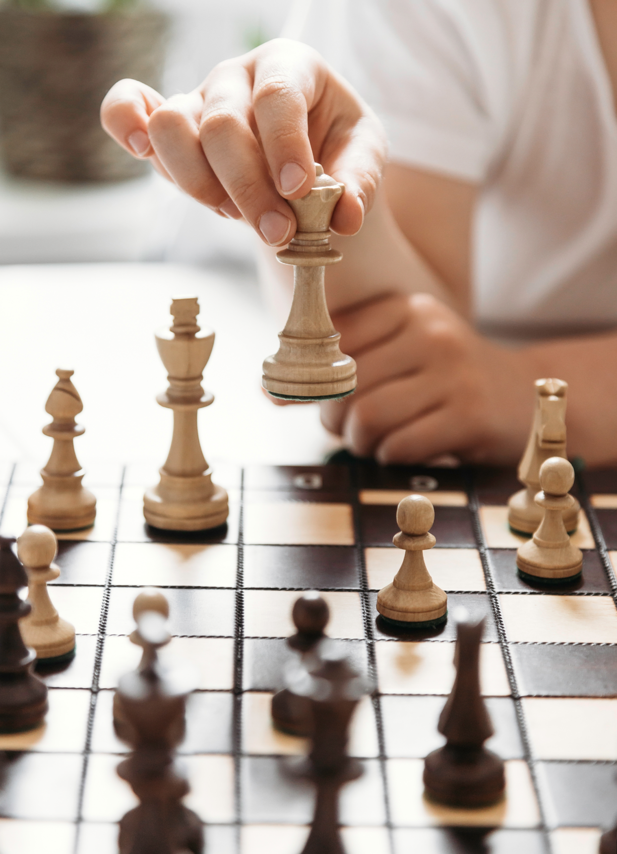 Hand moving a white king piece on a wooden chessboard during a game.