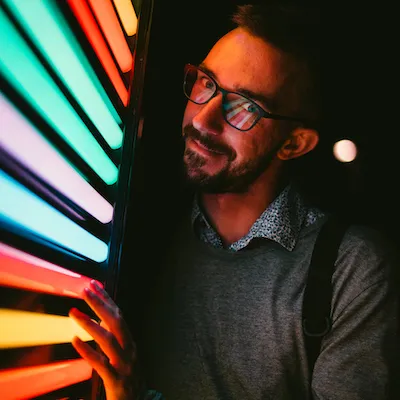 Vlad in profile, lit by a wall of colorful neon tubes.