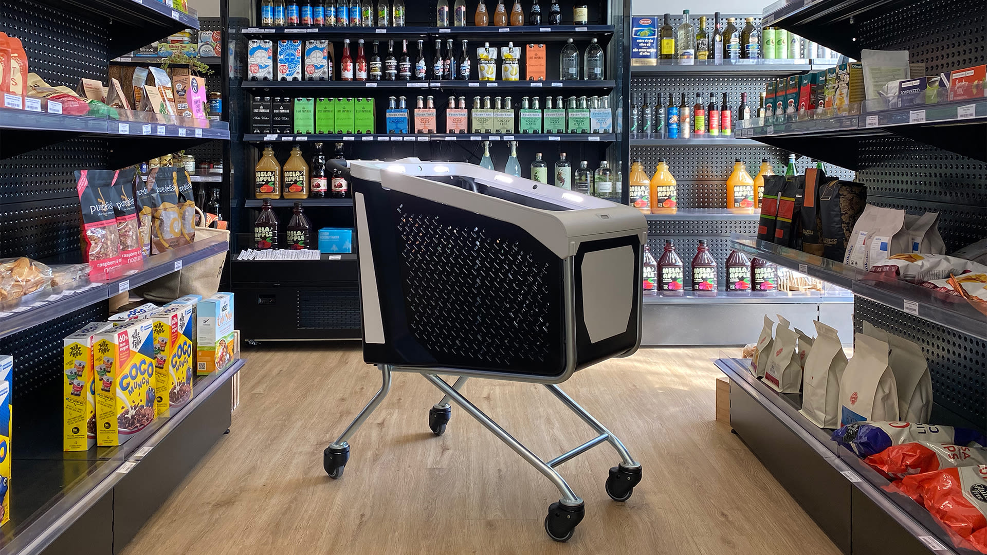 An Imagr smart shopping cart standing in a supermarket aisle between shelves of groceries