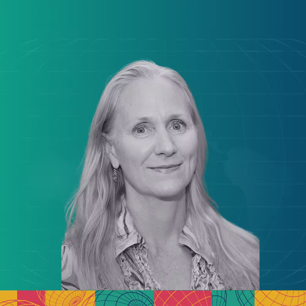 Smiling woman with glasses, shoulder-length hair, wearing a buttoned shirt and beaded necklace, against a teal and blue gradient background with geometric patterns.