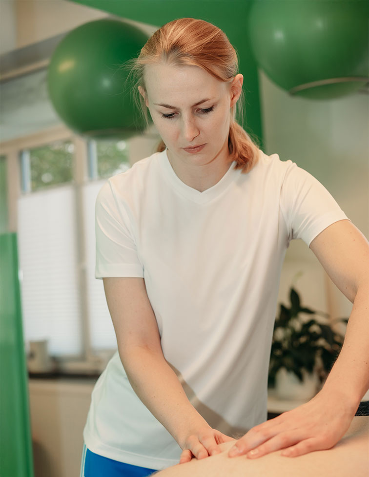Frau in weißem T-Shirt führt eine Massage in einem hellen Raum mit grünen Gymnastikbällen durch.