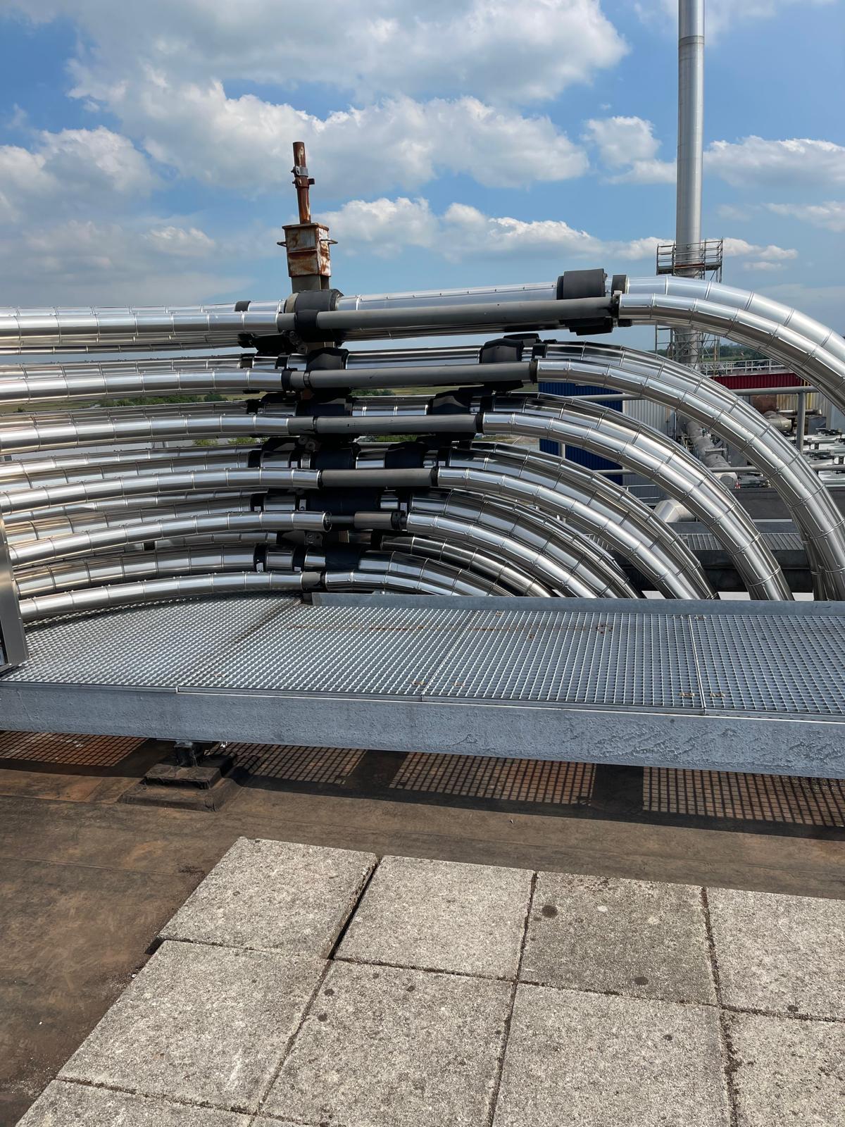 Leidingbundel op het dak: met aluminium beplate leidingen die in parallelle gesegmenteerde bochten lopen