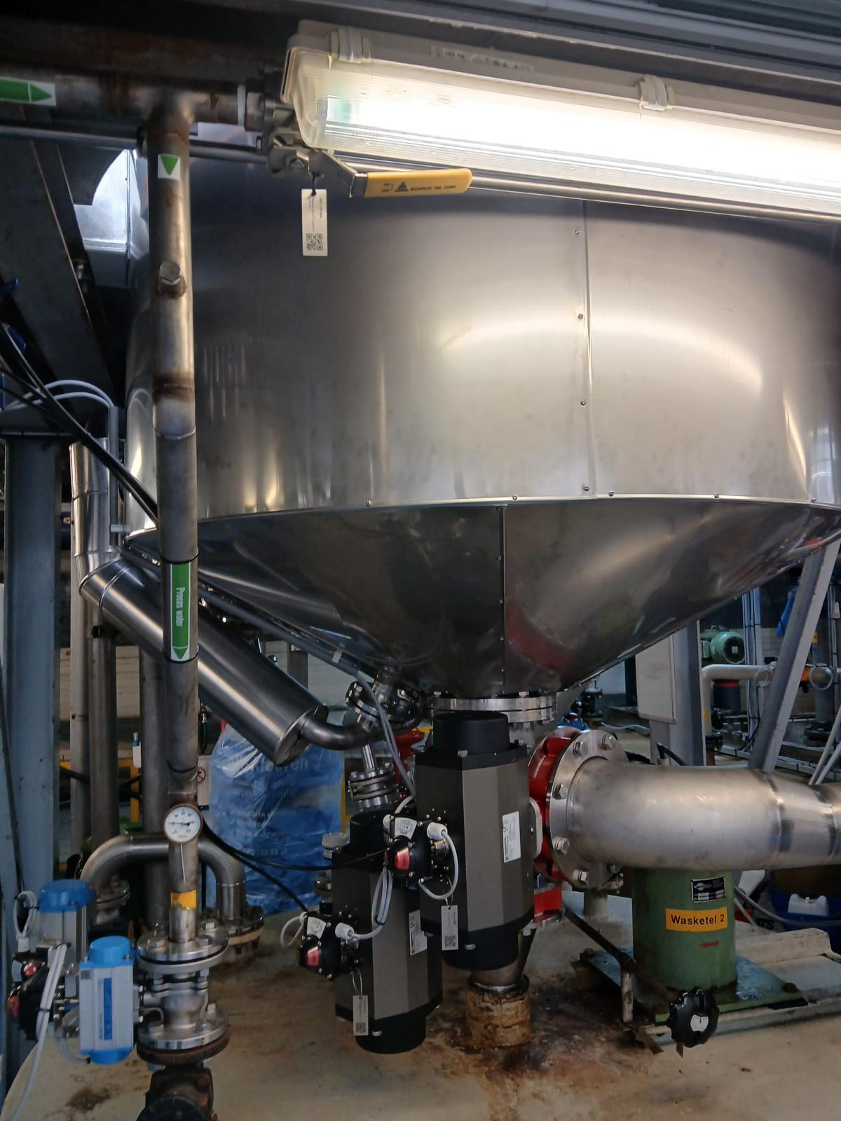 Conisch procesvat afgewerkt met RVS-beplating, met afsluiters, aandrijvingen en leidingwerk eronder aangesloten