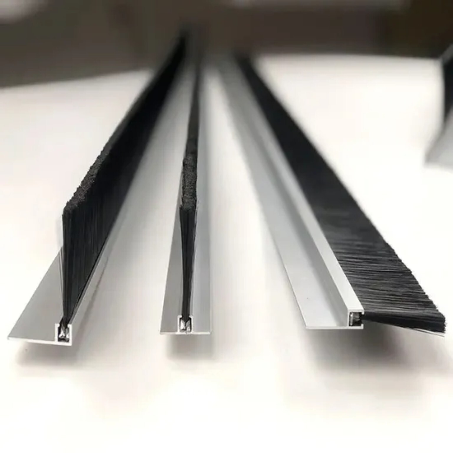 Drie borstelstrips met zwarte haren in metalen profielen