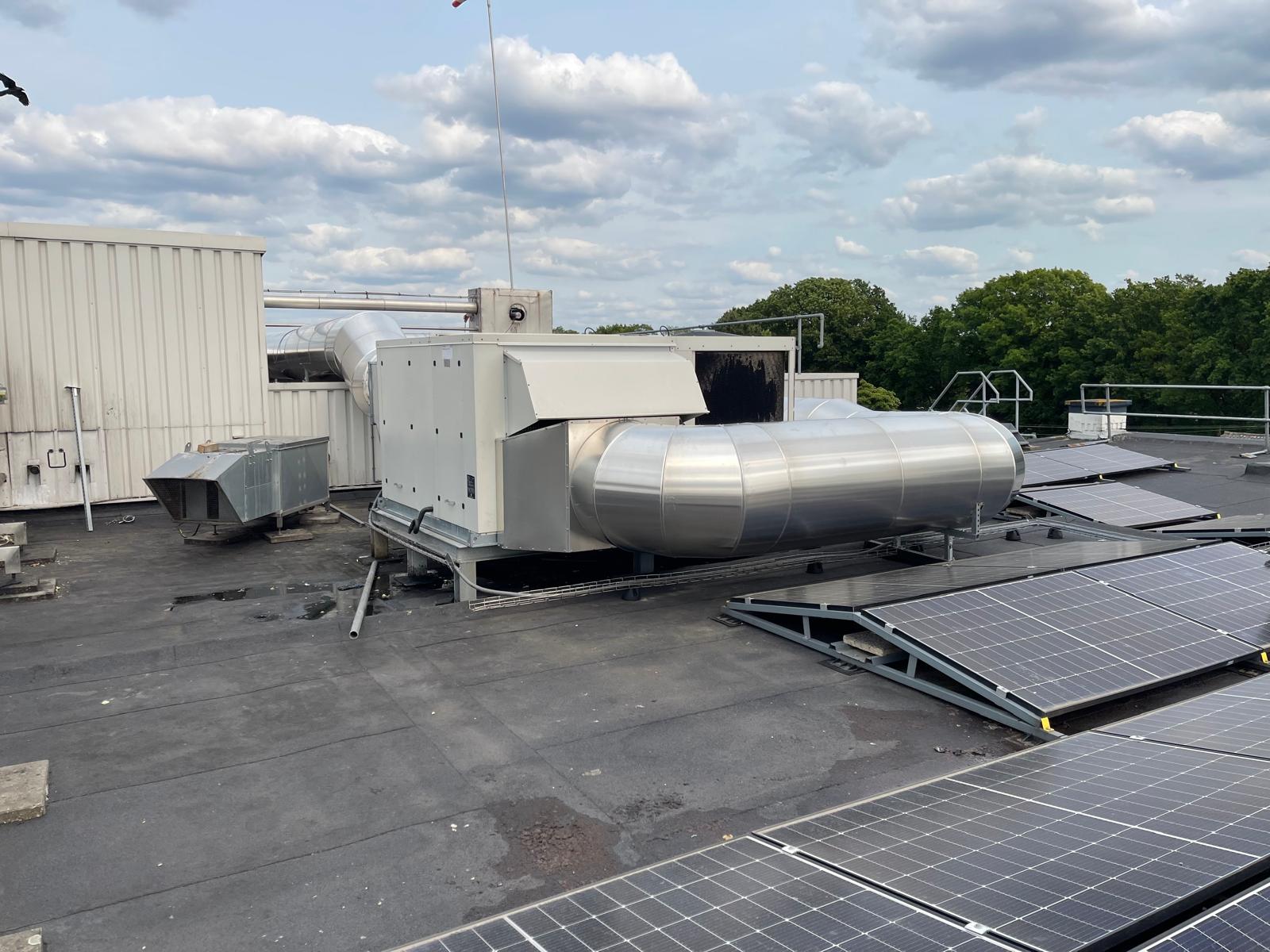 Met aluminium beplaat kanaal aangesloten op een dakunit naast zonnepanelen