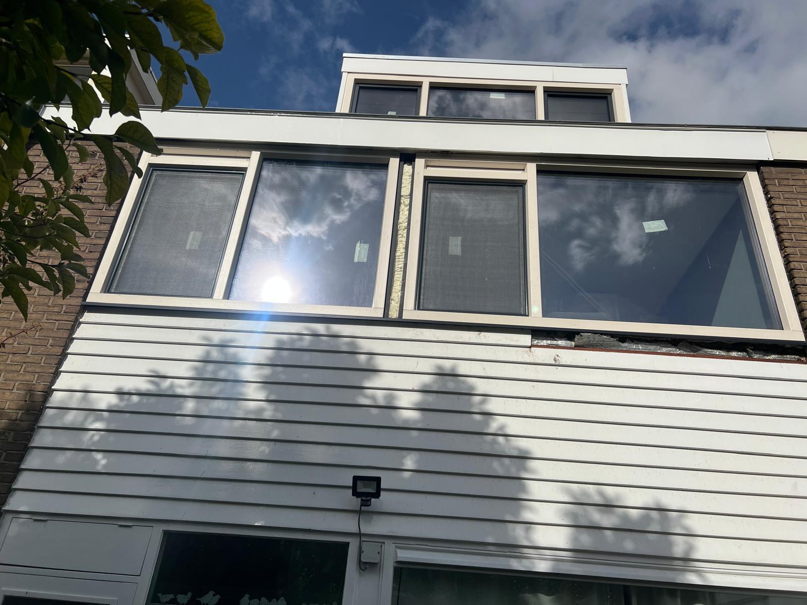 Voorgevel van een woning met verouderde kozijnen en lichte gevelbekleding vóór de werkzaamheden