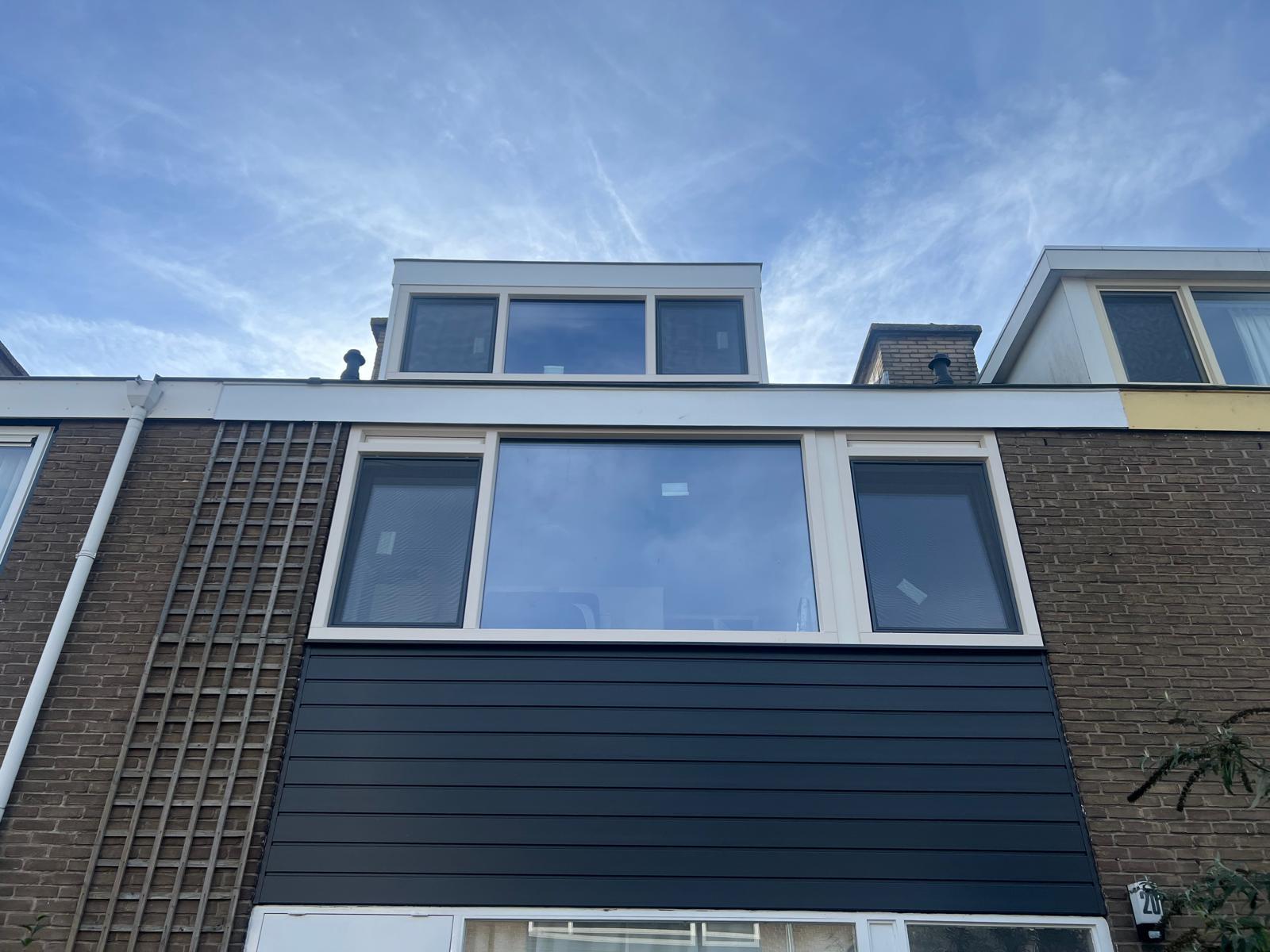 Rijwoning met vernieuwde witte kozijnen in de voorgevel, een grote glaspartij op de eerste verdieping en een dakkapel