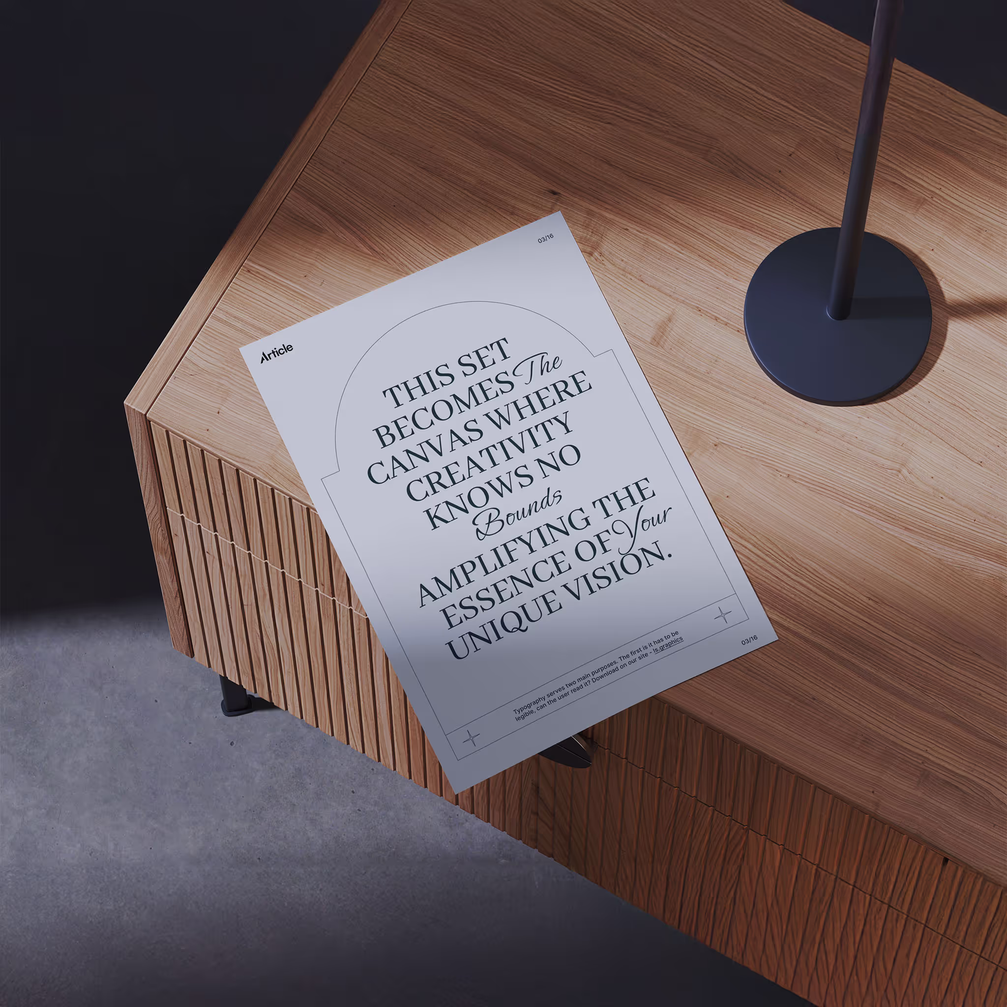 Printed sheet with inspirational typography about creativity resting on a wooden textured cabinet next to a lamp base.