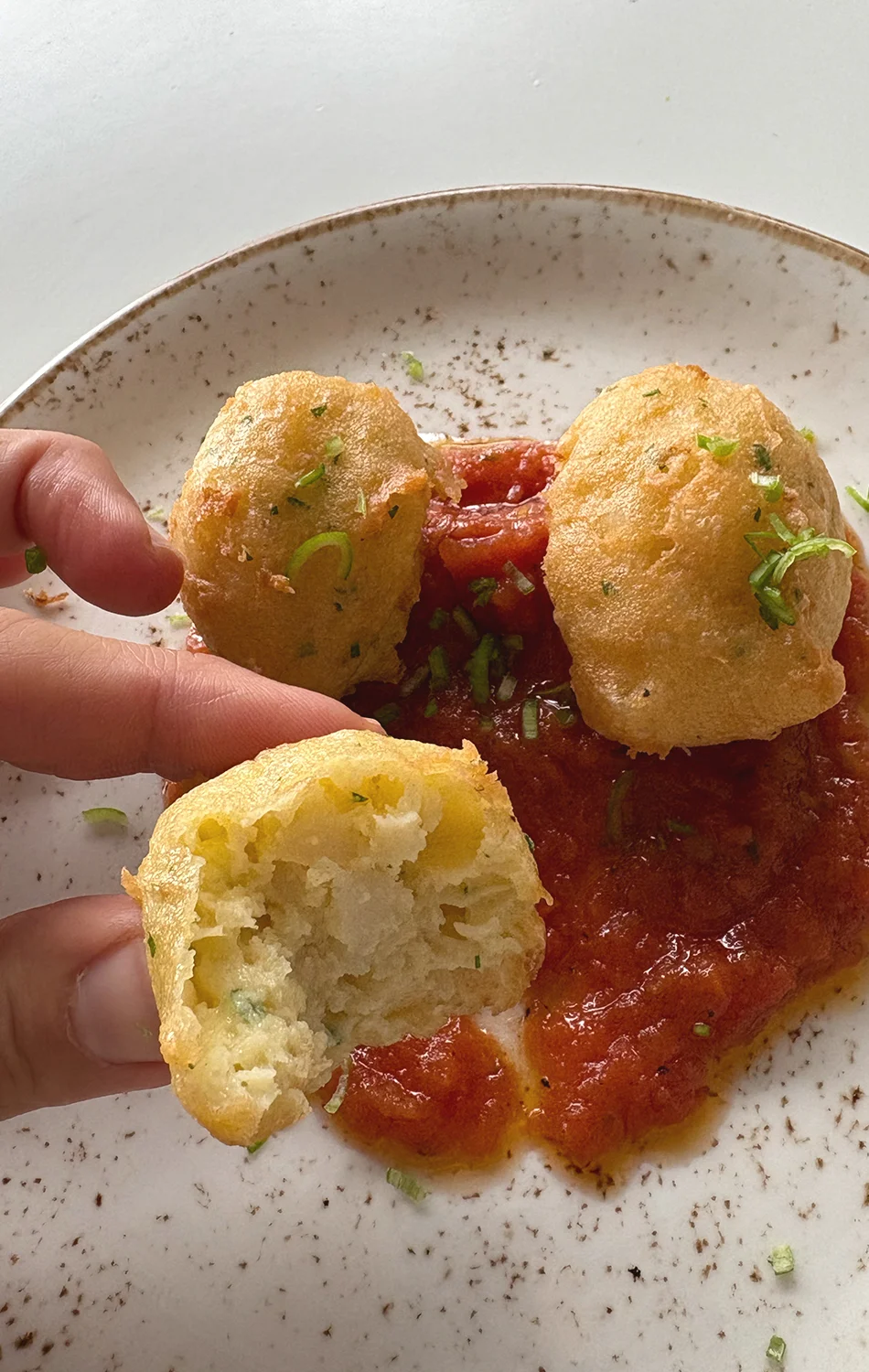 Close-up of a baked vegetable quiche topped with grilled zucchini slices, asparagus, sun-dried tomatoes, and pine nuts in a ceramic pie dish.