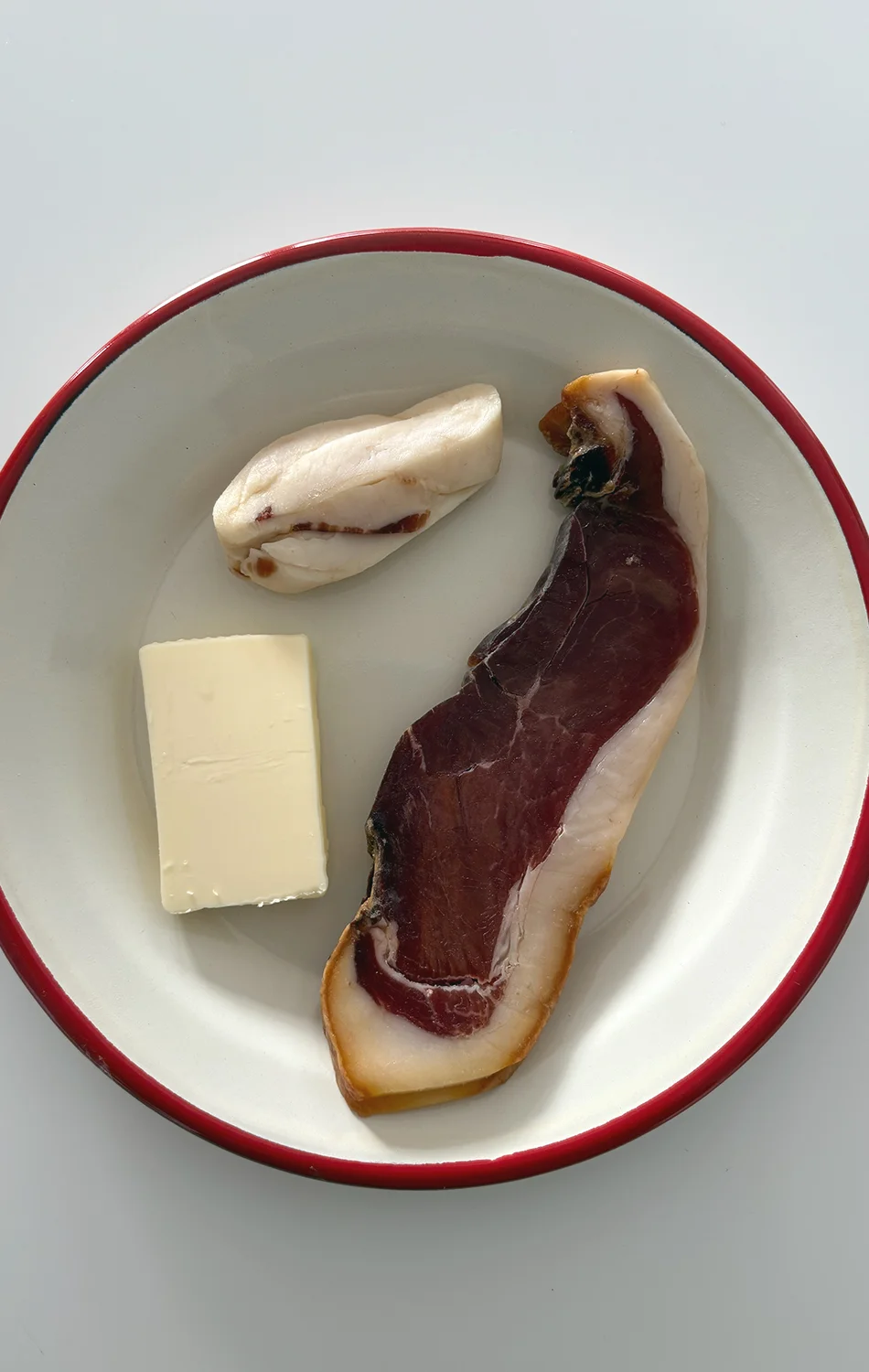 Close-up of a baked vegetable quiche topped with grilled zucchini slices, asparagus, sun-dried tomatoes, and pine nuts in a ceramic pie dish.