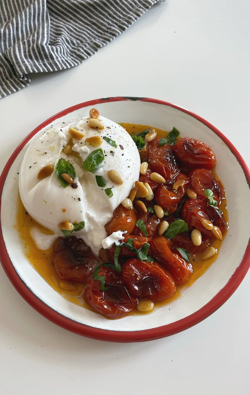 Three golden fried dough balls garnished with chopped herbs on a bed of red tomato sauce, served on a speckled white plate.
