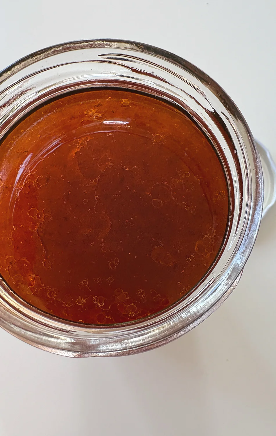 Close-up of a baked vegetable quiche topped with grilled zucchini slices, asparagus, sun-dried tomatoes, and pine nuts in a ceramic pie dish.