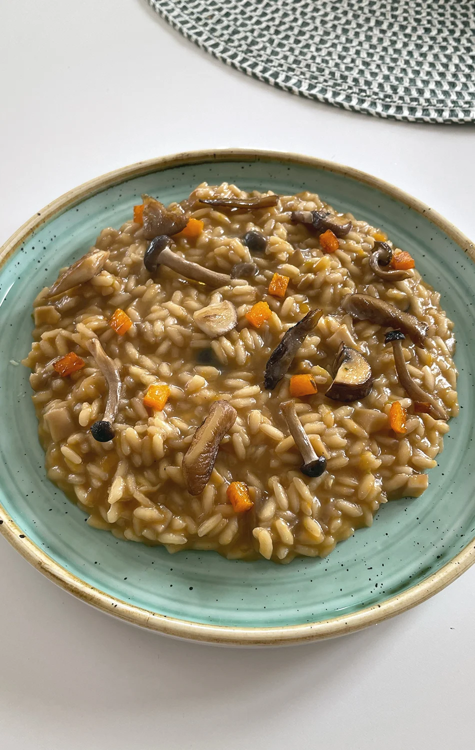 Three golden fried dough balls garnished with chopped herbs on a bed of red tomato sauce, served on a speckled white plate.