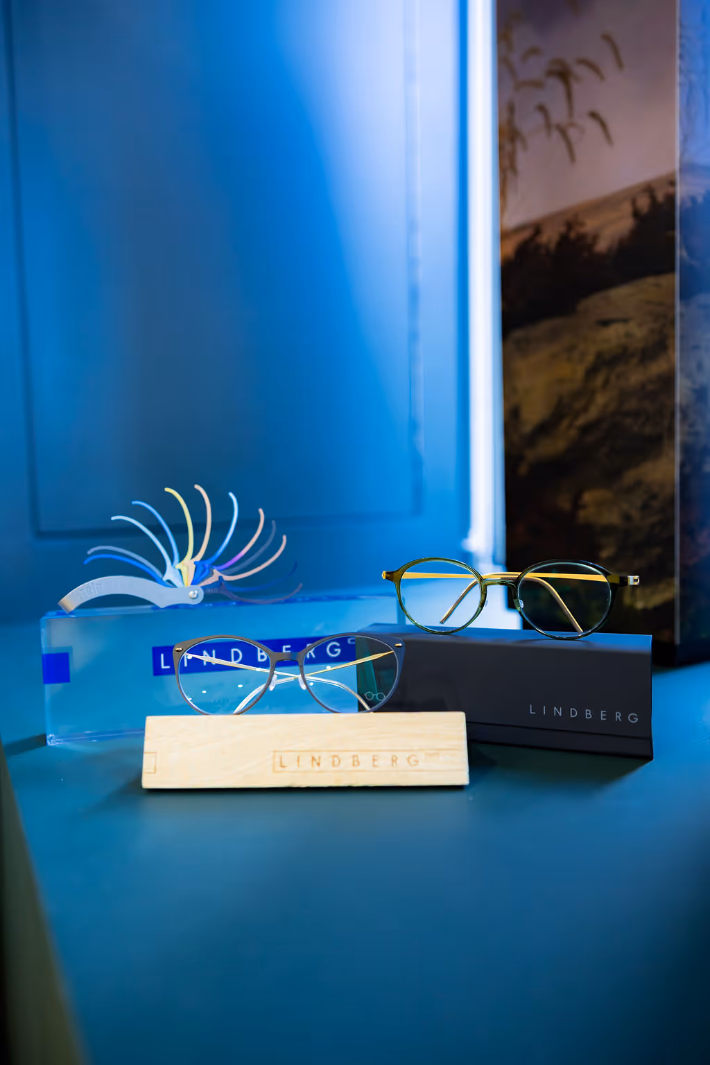 Lindberg glasses on wooden stand with blue background and packaging
