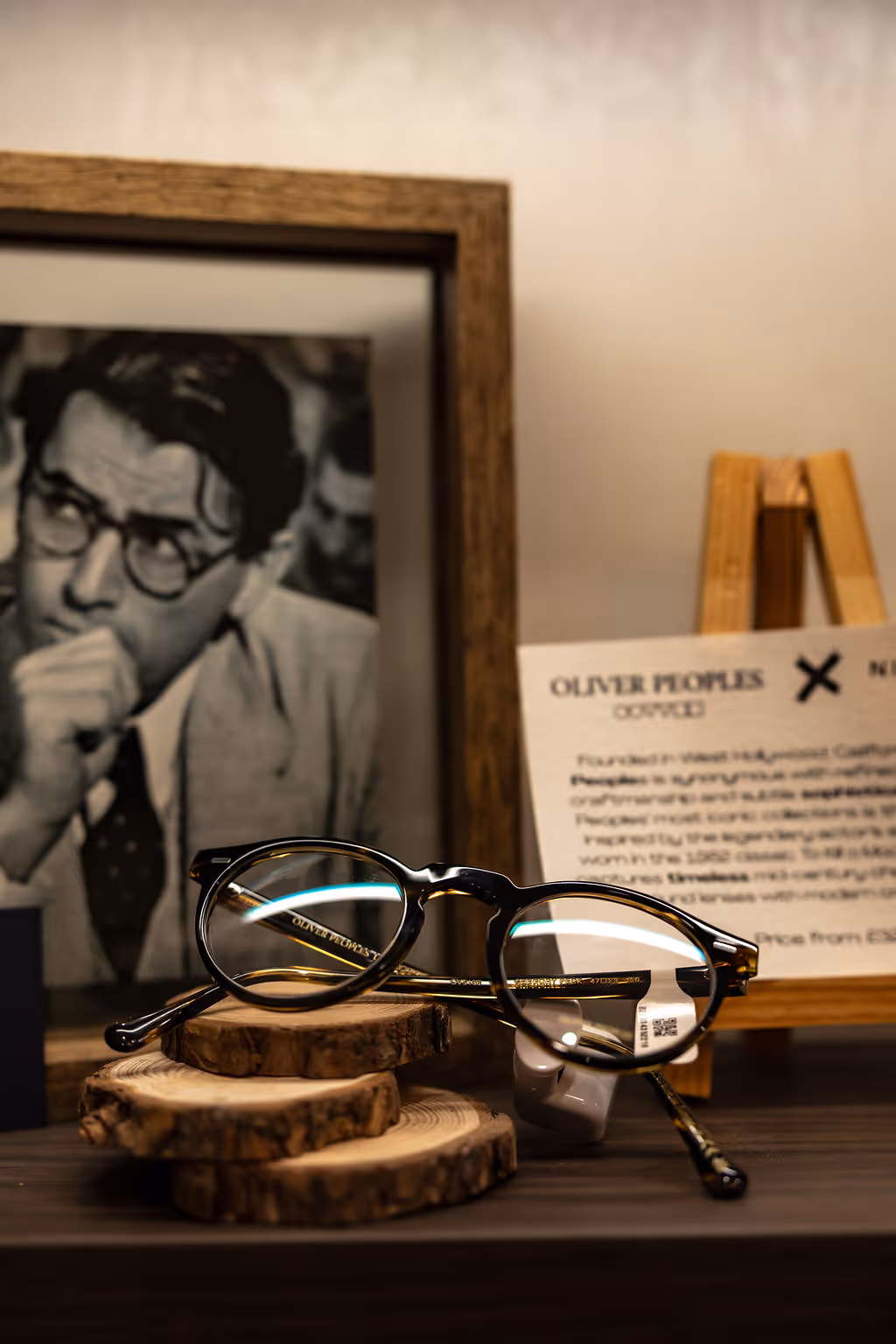 Vintage Oliver Peoples glasses on wooden discs with framed black and white portrait