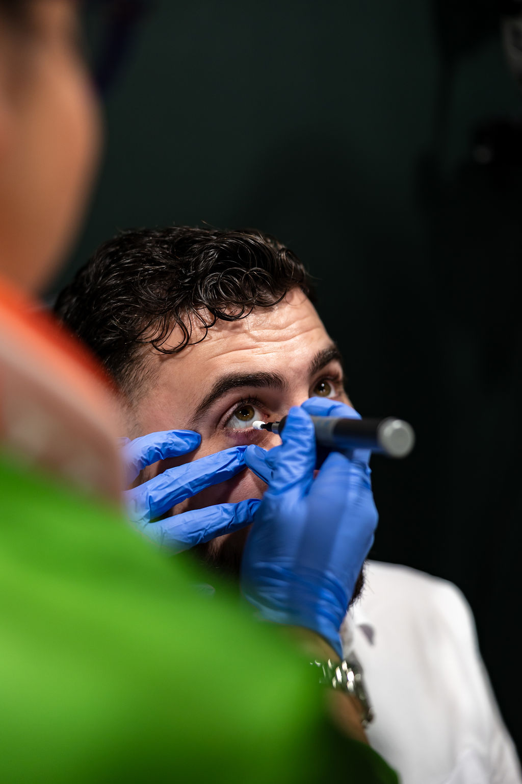 Eye exam with medical professional using blue gloves and diagnostic tool