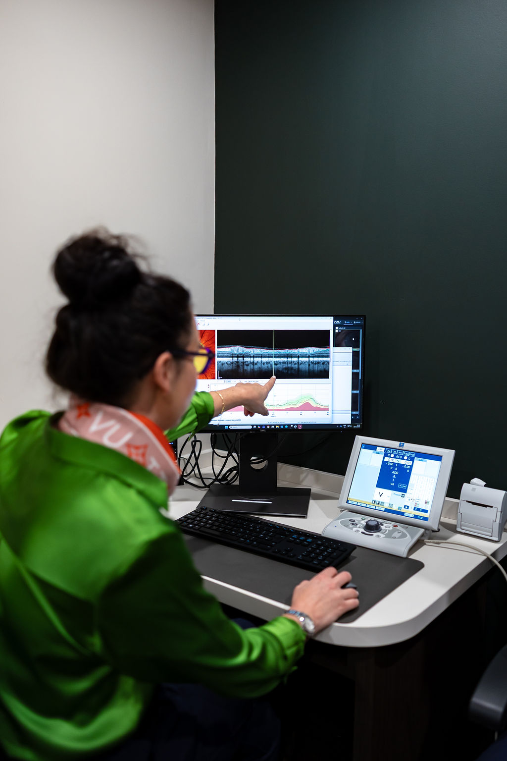 Researcher analyzing data on computer screen with medical monitoring equipment