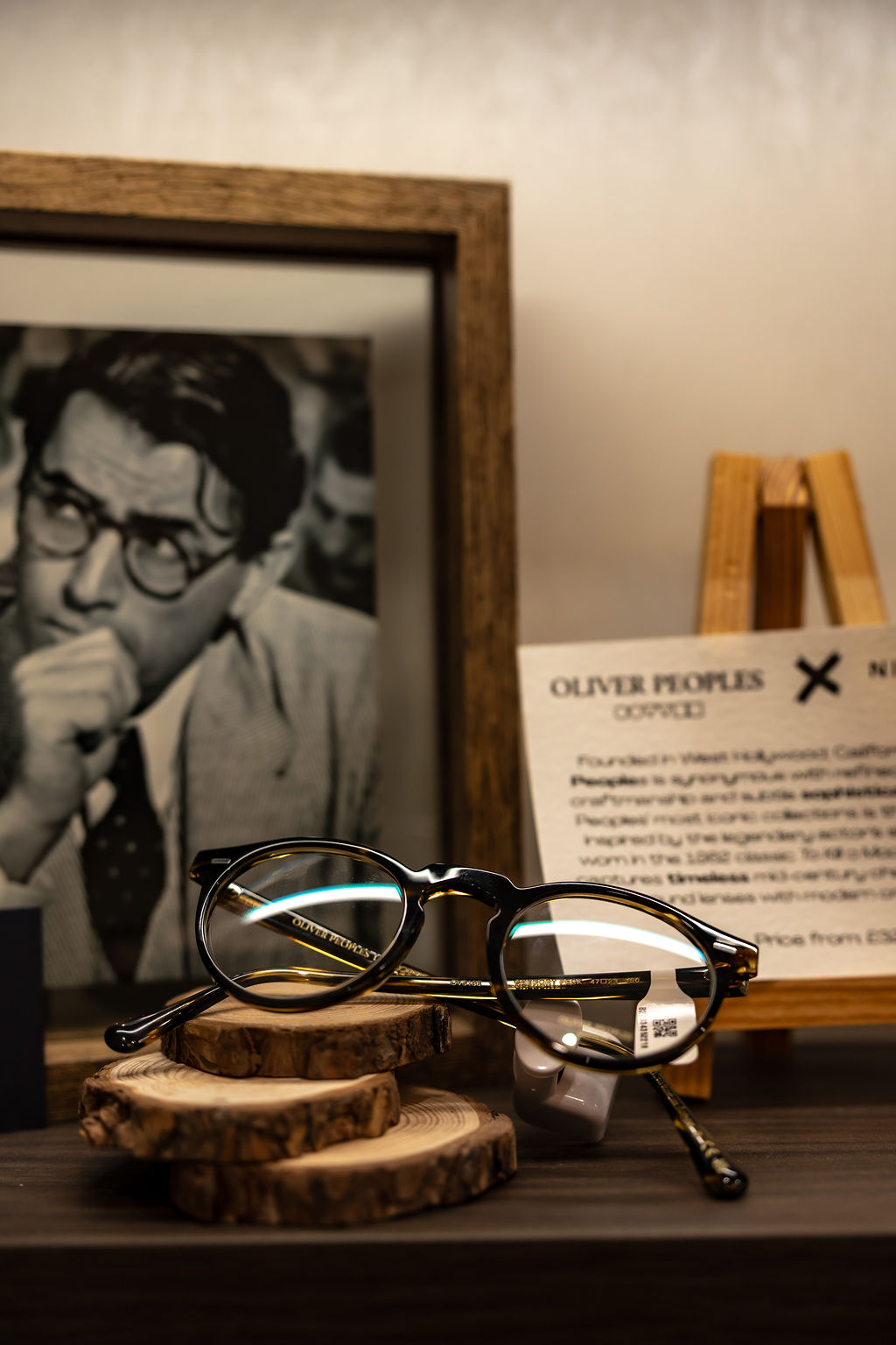 Oliver Peoples glasses on wooden slice with vintage portrait and document