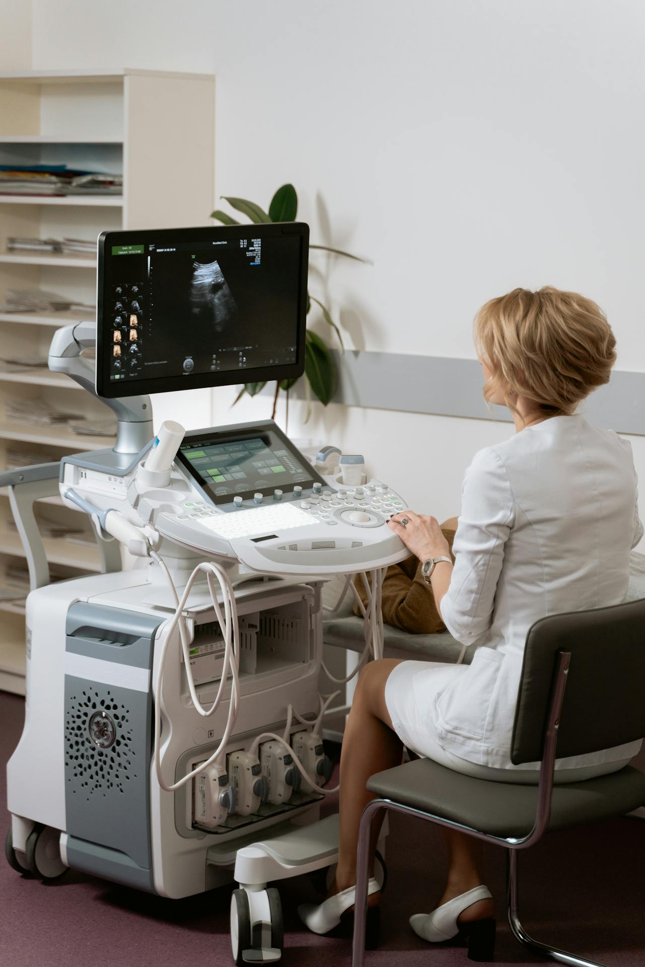 Medical professional using ultrasound machine, viewing ultrasound image on the monitor in a clinic room.