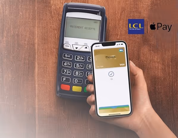 Hand holding smartphone displaying Apple Pay Visa card near payment terminal with 'paiement accepte' message.