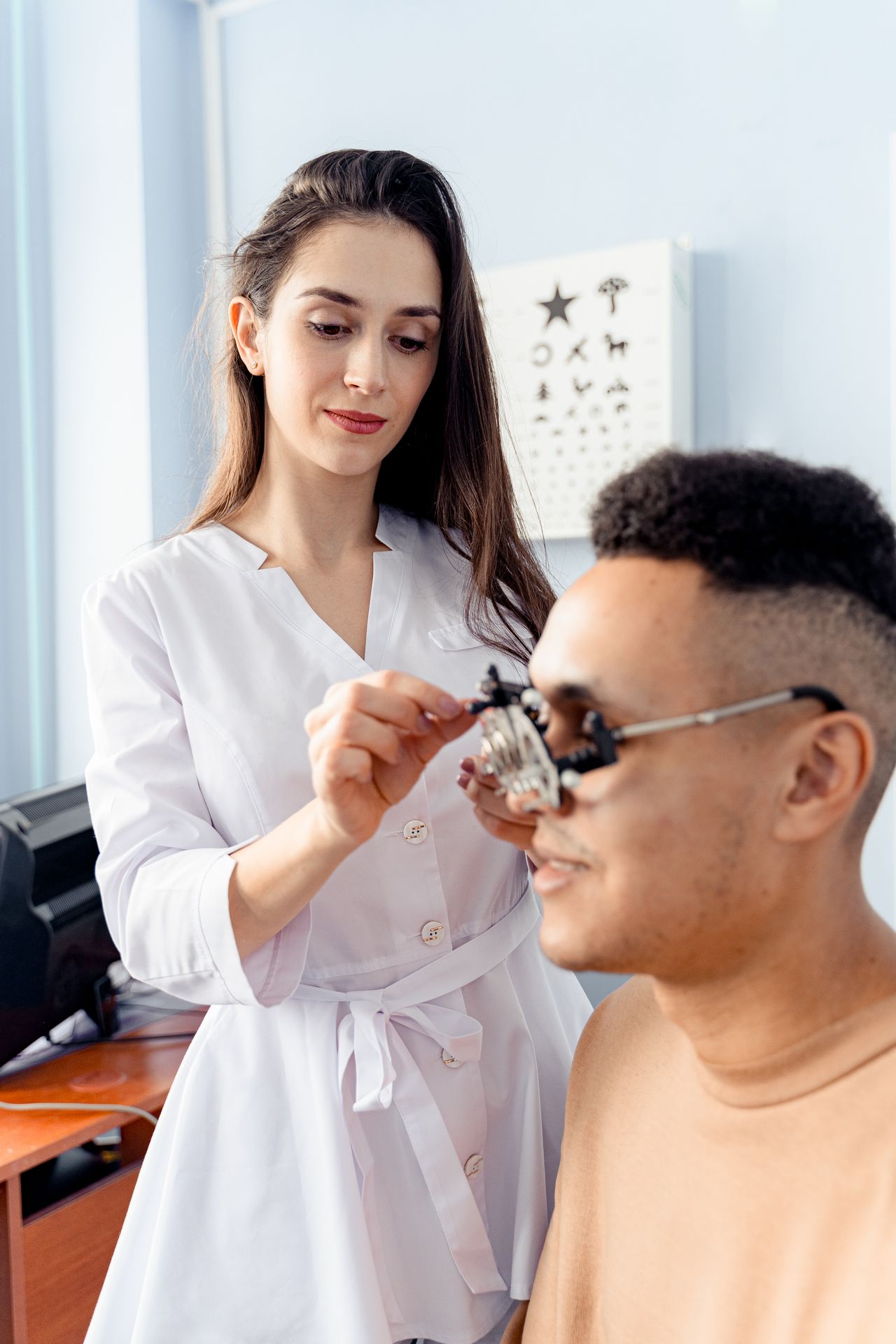 Optometrist adjusting trial frame on patient’s face during eye exam in medical office.