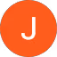Oranssi ympyrä, jossa valkoinen kirjain "J" keskellä, mustalla taustalla.