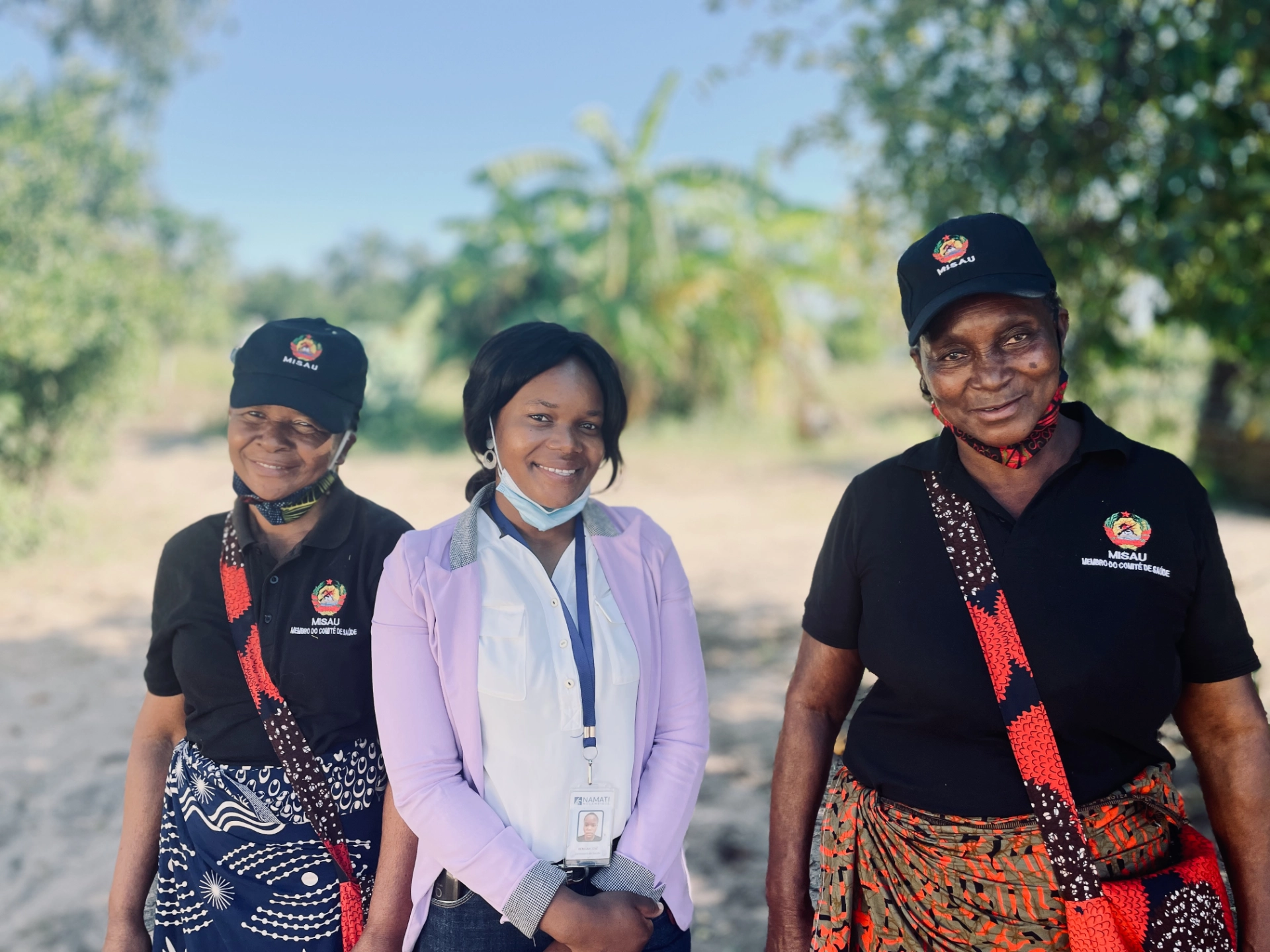 Two health committee volunteers standing with a Matimba staff member outdoors