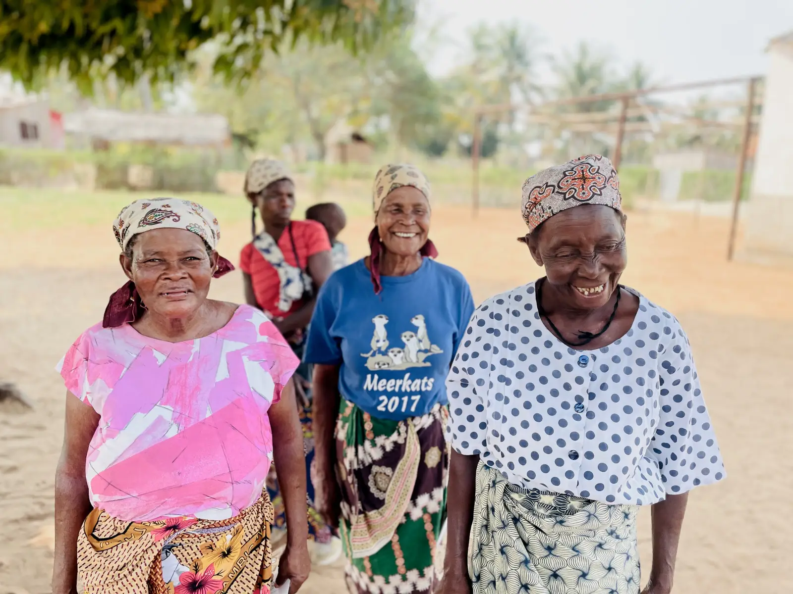 Three older women smiling together outdoors in their community