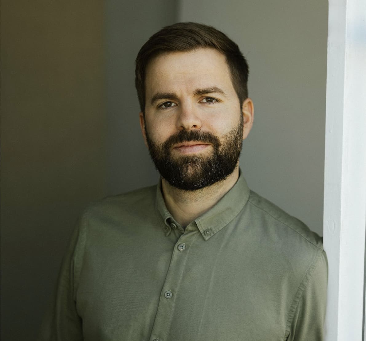 man with beard smiling, gray background