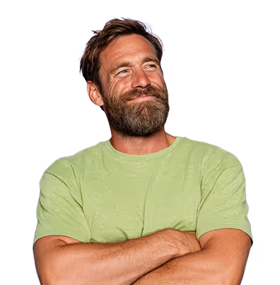 Hombre de mediana edad con barba y camiseta verde clara, sonriendo con los brazos cruzados.