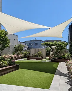 Mesa de comedor de madera con seis sillas de mimbre gris en césped artificial al aire libre.
