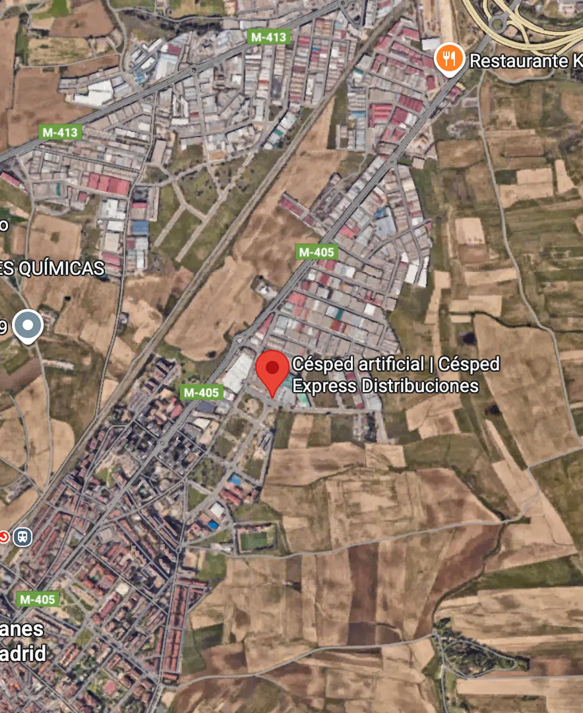 Mapa satelital que muestra un área con campos y zonas urbanas, con un marcador en Cesped artificial | Cerca de la carretera M-405.