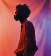 Woman in white dress sitting with arms resting on knees in soft lighting.