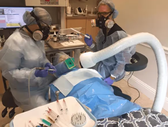 Two dental workers performing a dental treatment on a patient