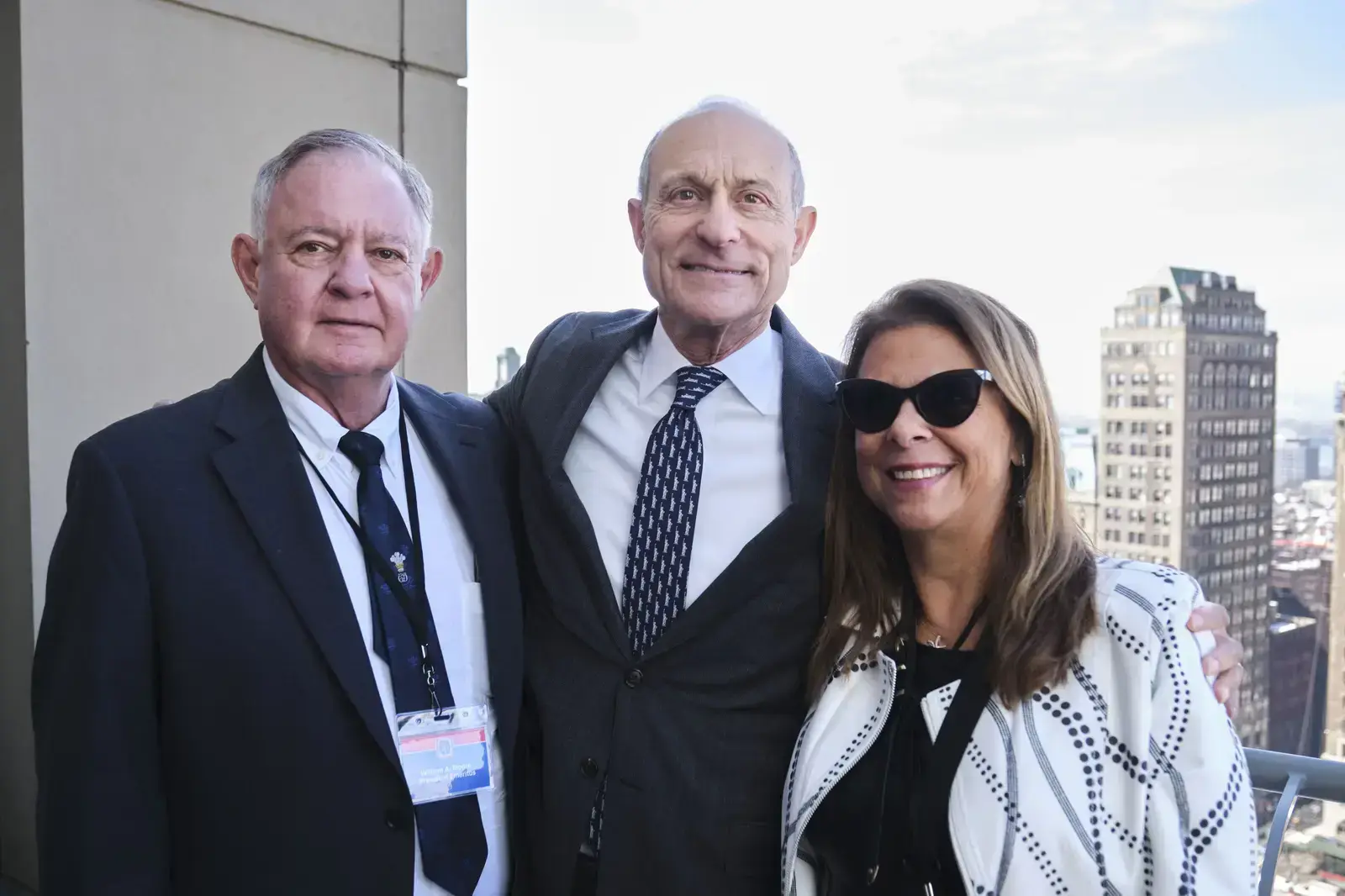Three professionals posing together at a rooftop event