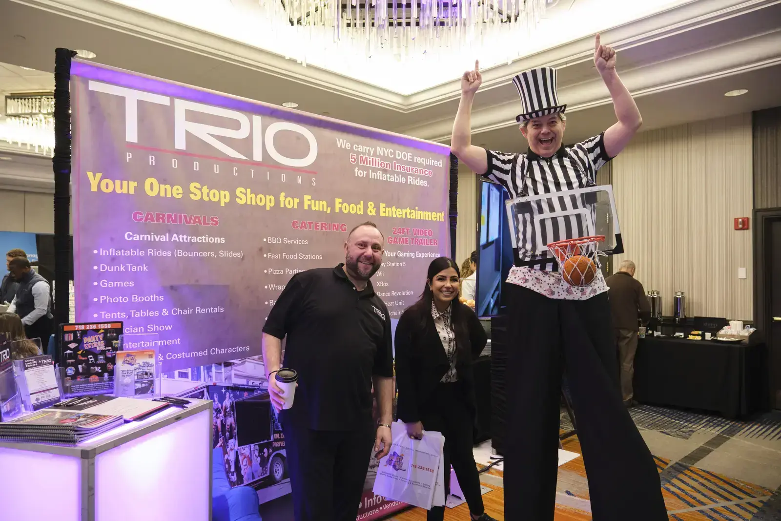 Three people posing at TRIO Productions carnival entertainment booth