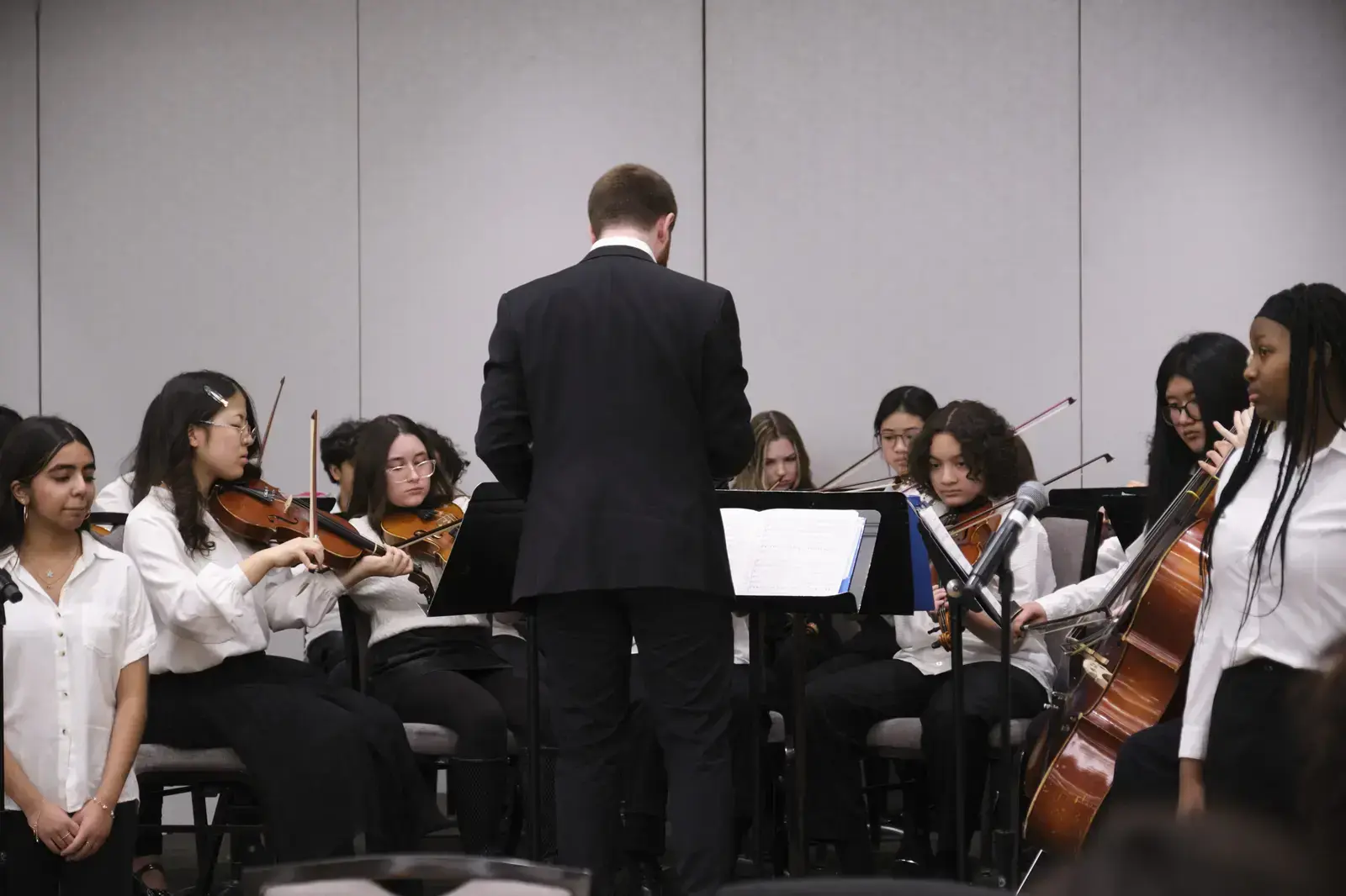 Conductor leading student orchestra during rehearsal performance