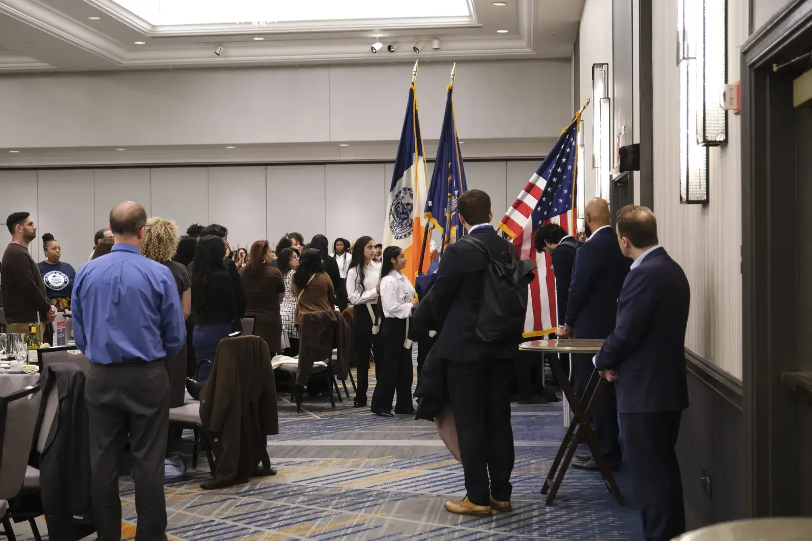 Attendees standing during flag ceremony at formal event