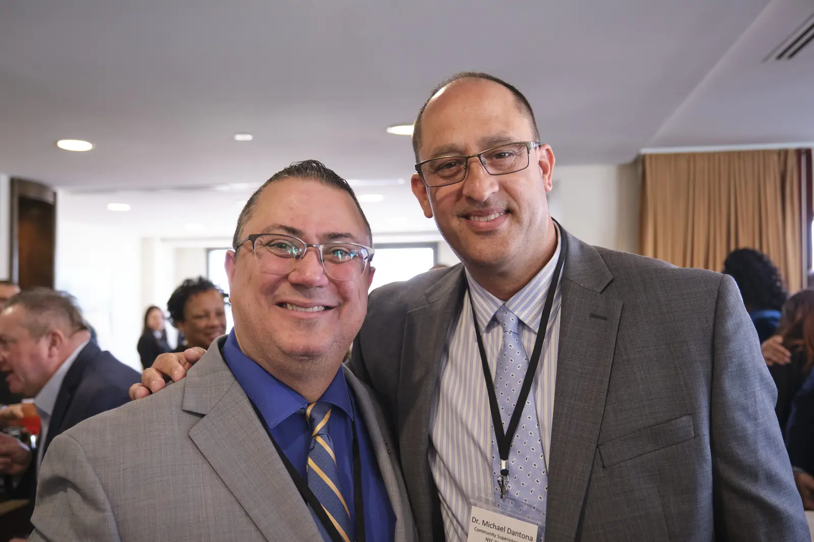 Two colleagues smiling together at a professional school event