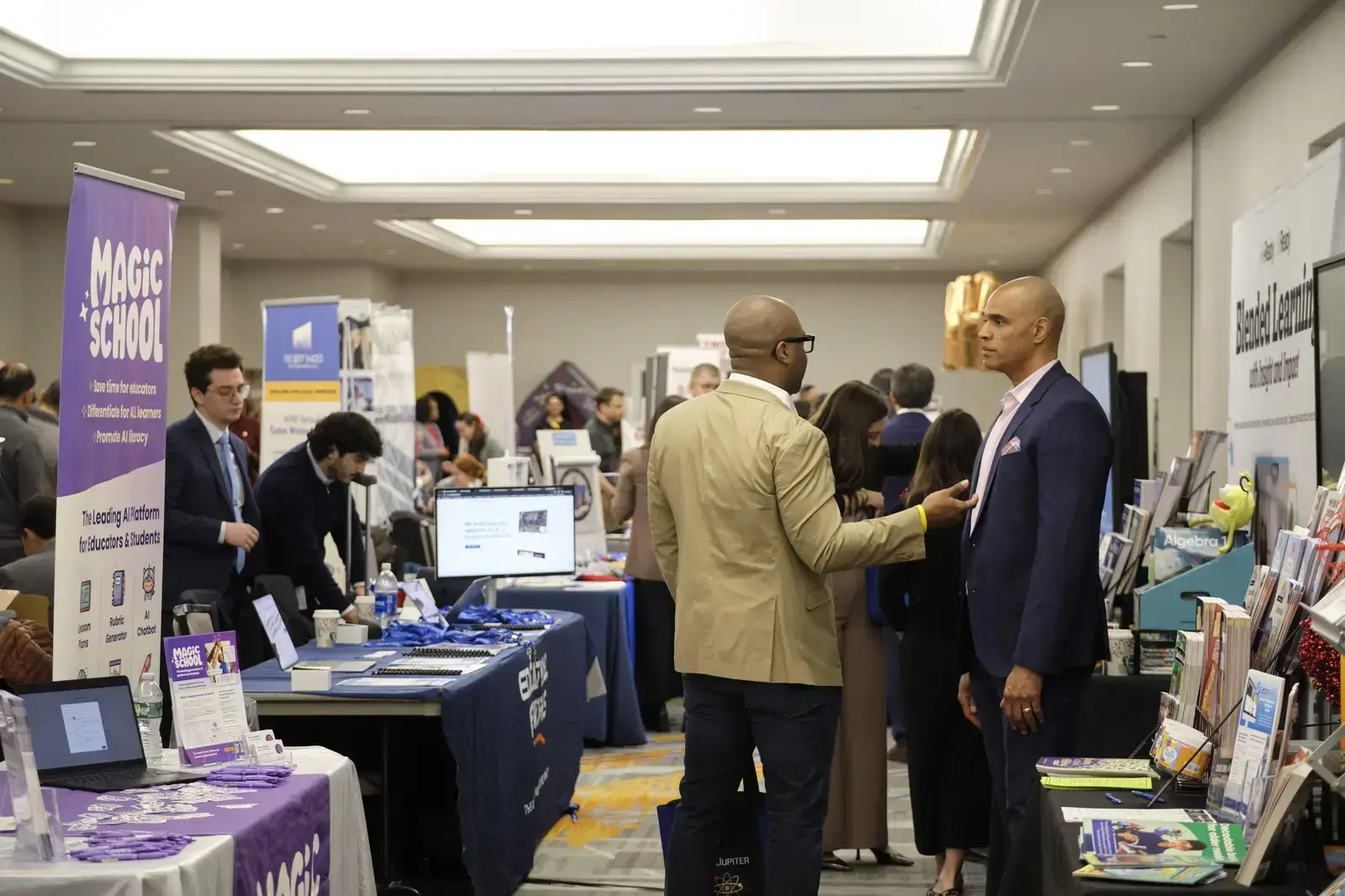 Attendees networking at educational resource fair with school program booths